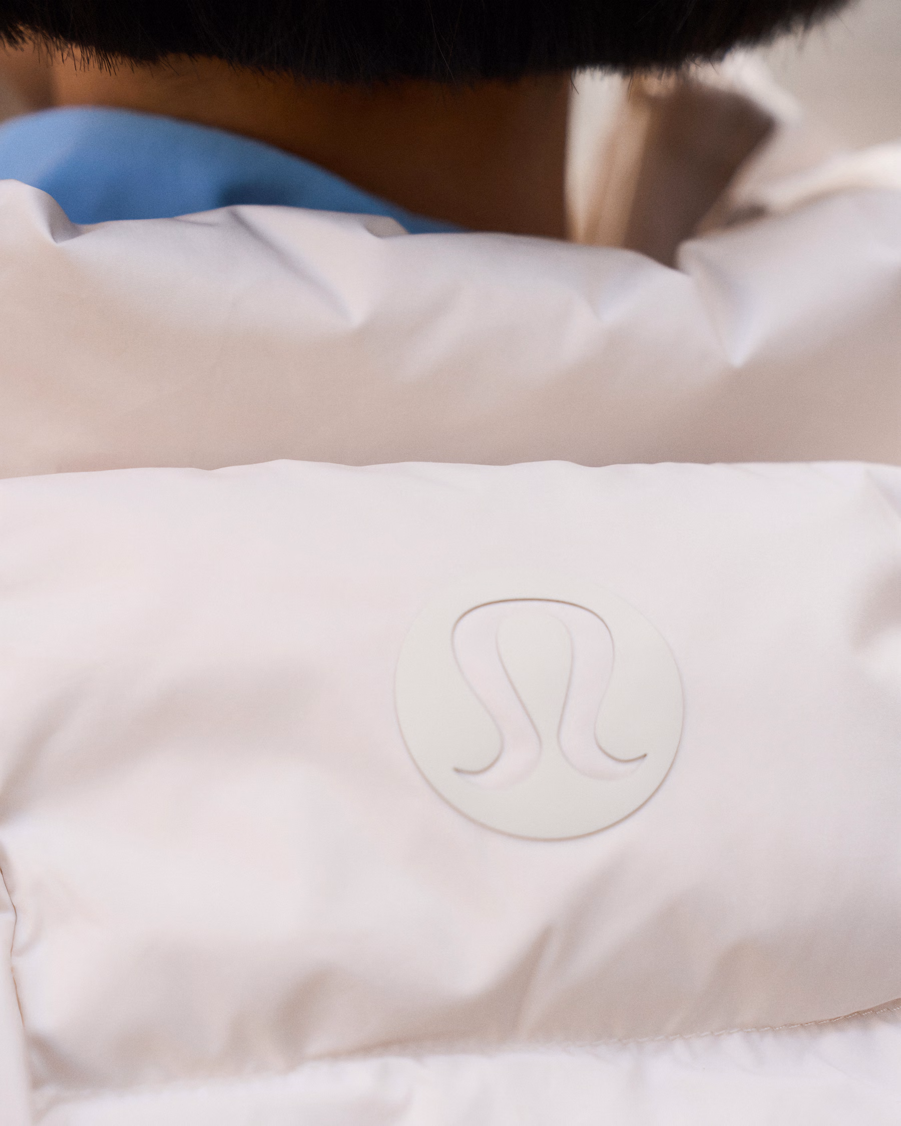 ภาพใกล้ของลายควิลต์และโลโก้บนแจ็กเก็ตครอป Wunder Puff ภาพจาก lululemon