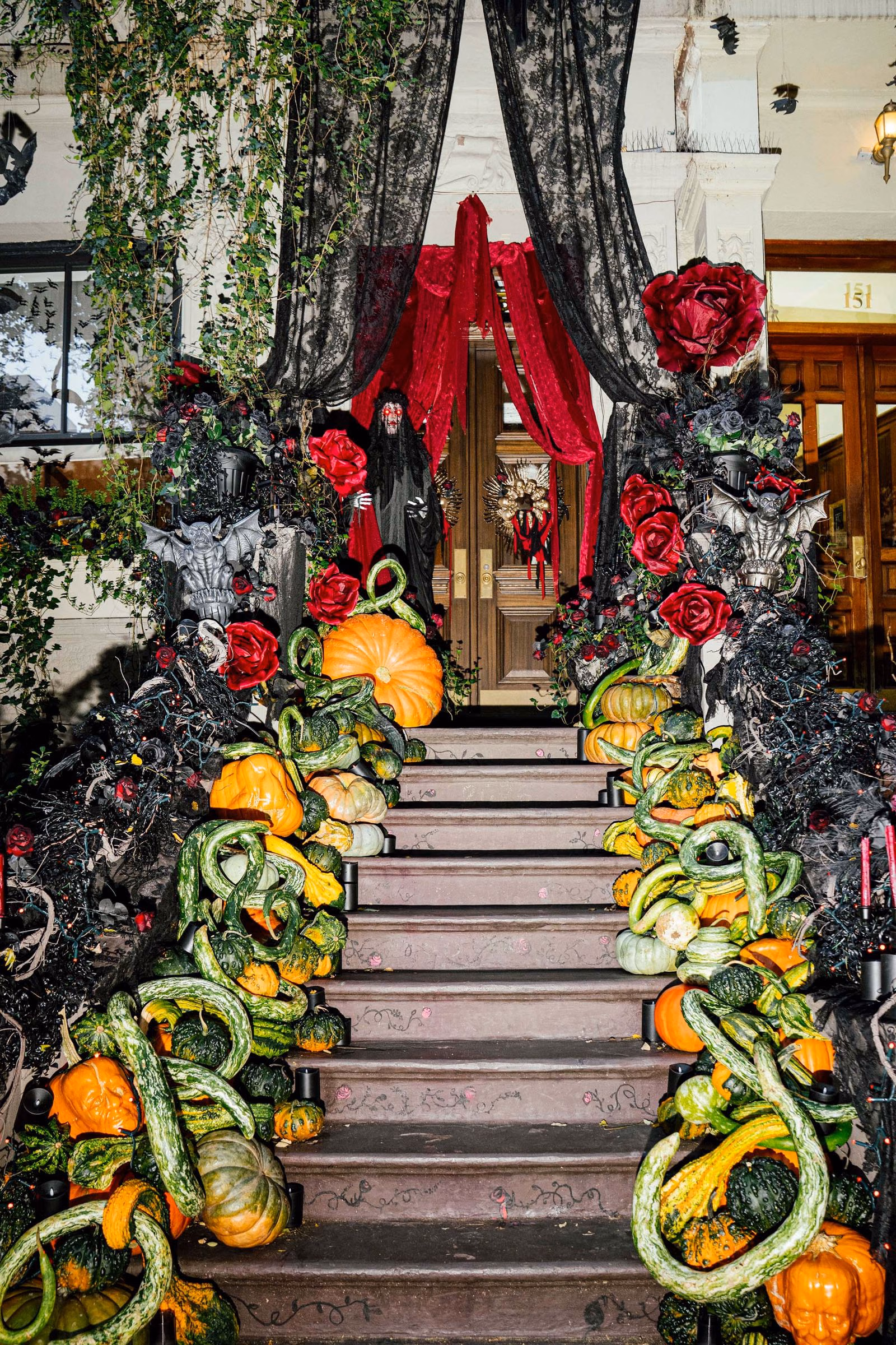 A Gothic residential entrance framed by black draping, red roses and pumpkins