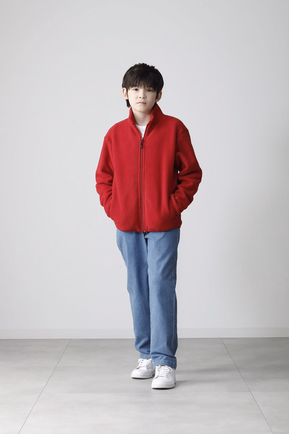 นายแบบเด็กใส่ฟลีซซิปเต็มสีแดงและเอามือในกระเป๋า