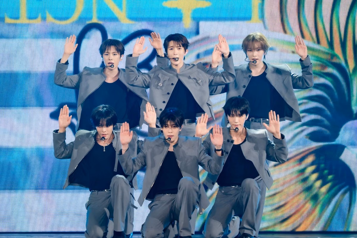 NCT WISH in grey suits and dark inner layers perform a coordinated hand gesture