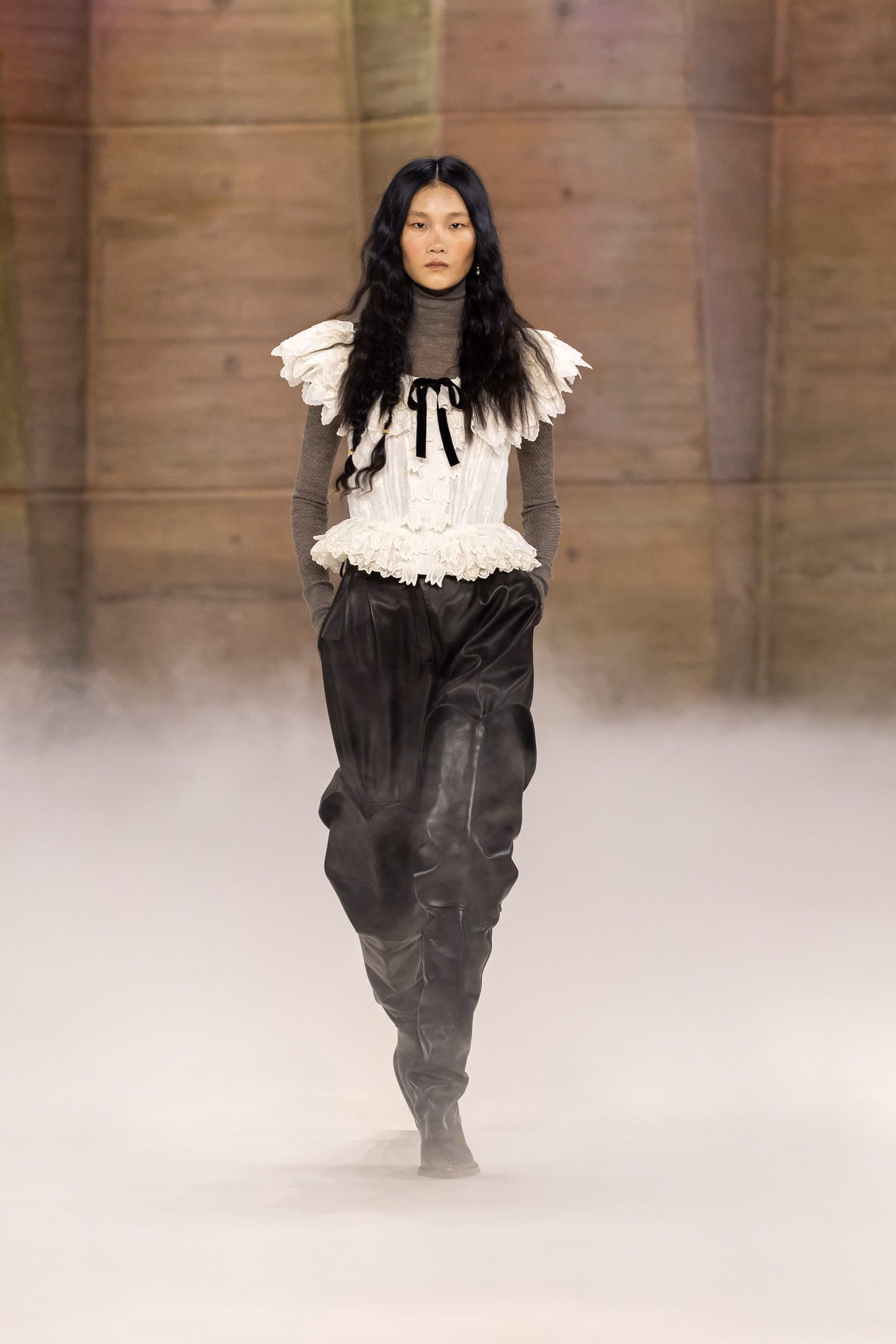 A white Chloé ruffled top over a grey turtleneck with black trousers