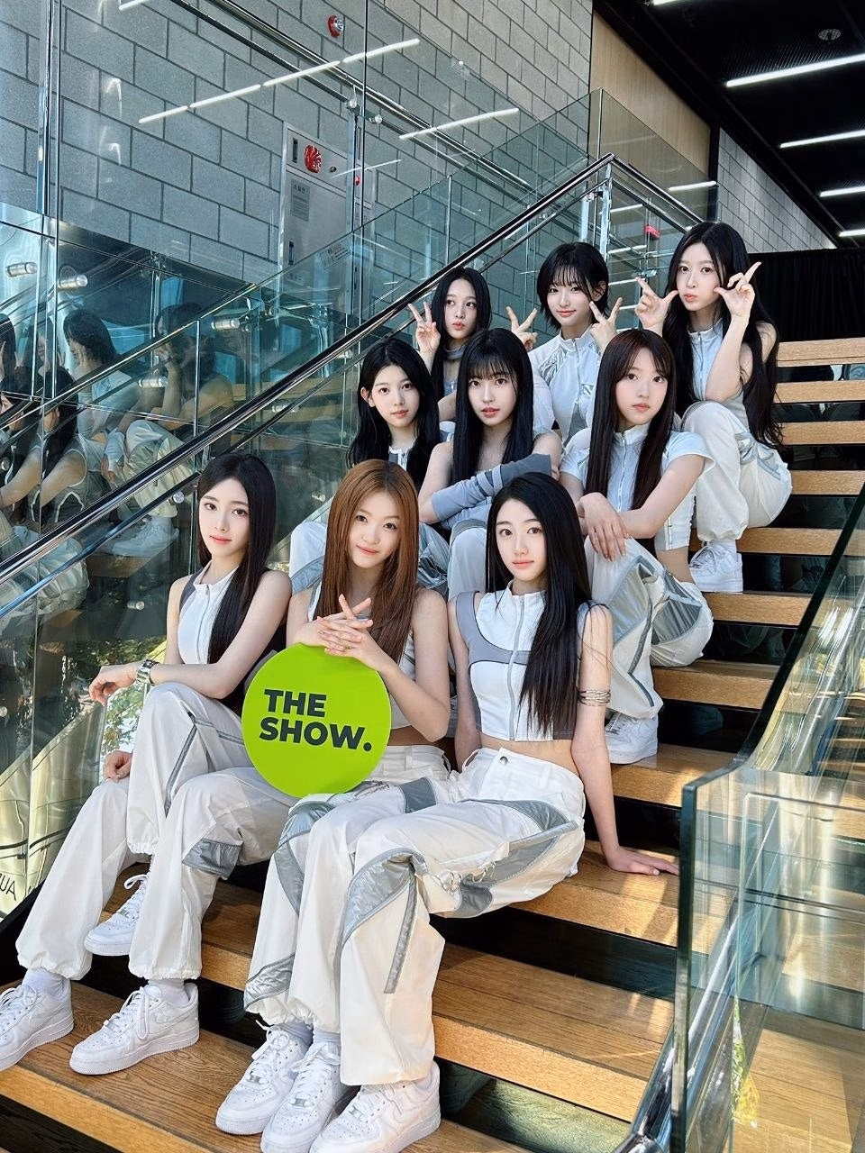 흰색·실버 의상으로 계단에 앉아 초록 THE SHOW 보드를 든 아홉 멤버의 10월20일 첫1위 관련사진