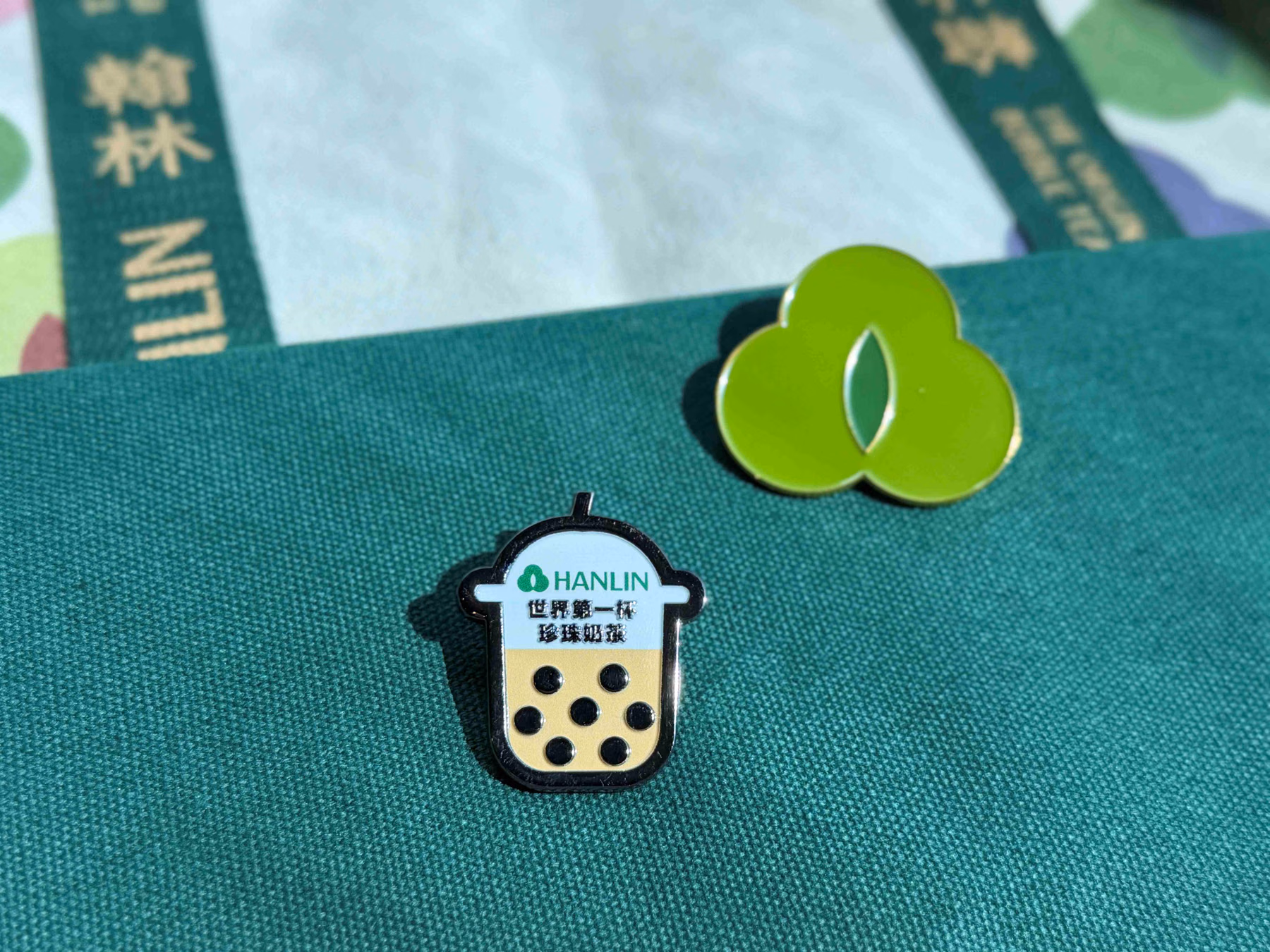 Hanlin leaf and pearl milk tea cup badges on green fabric