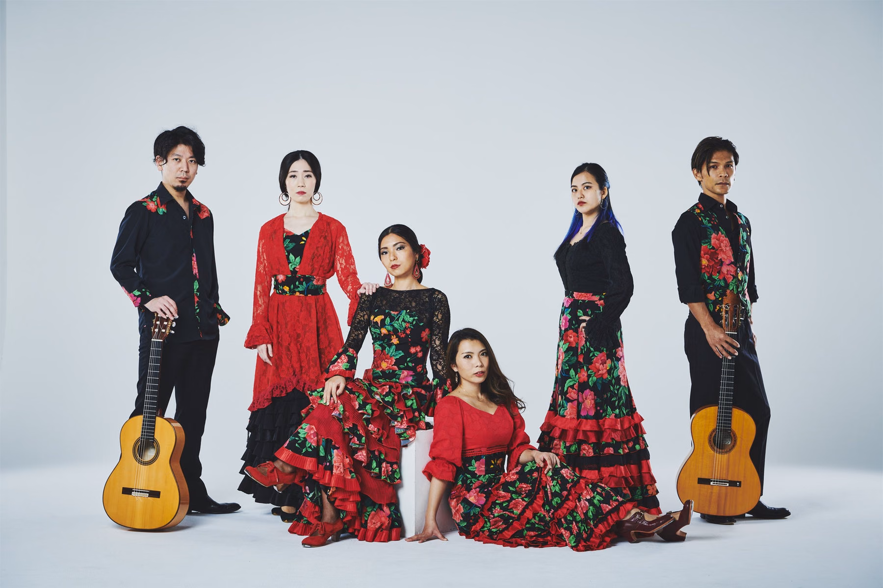 Los Topos團體形象照，成員穿紅黑花卉服裝，兩側放有吉他