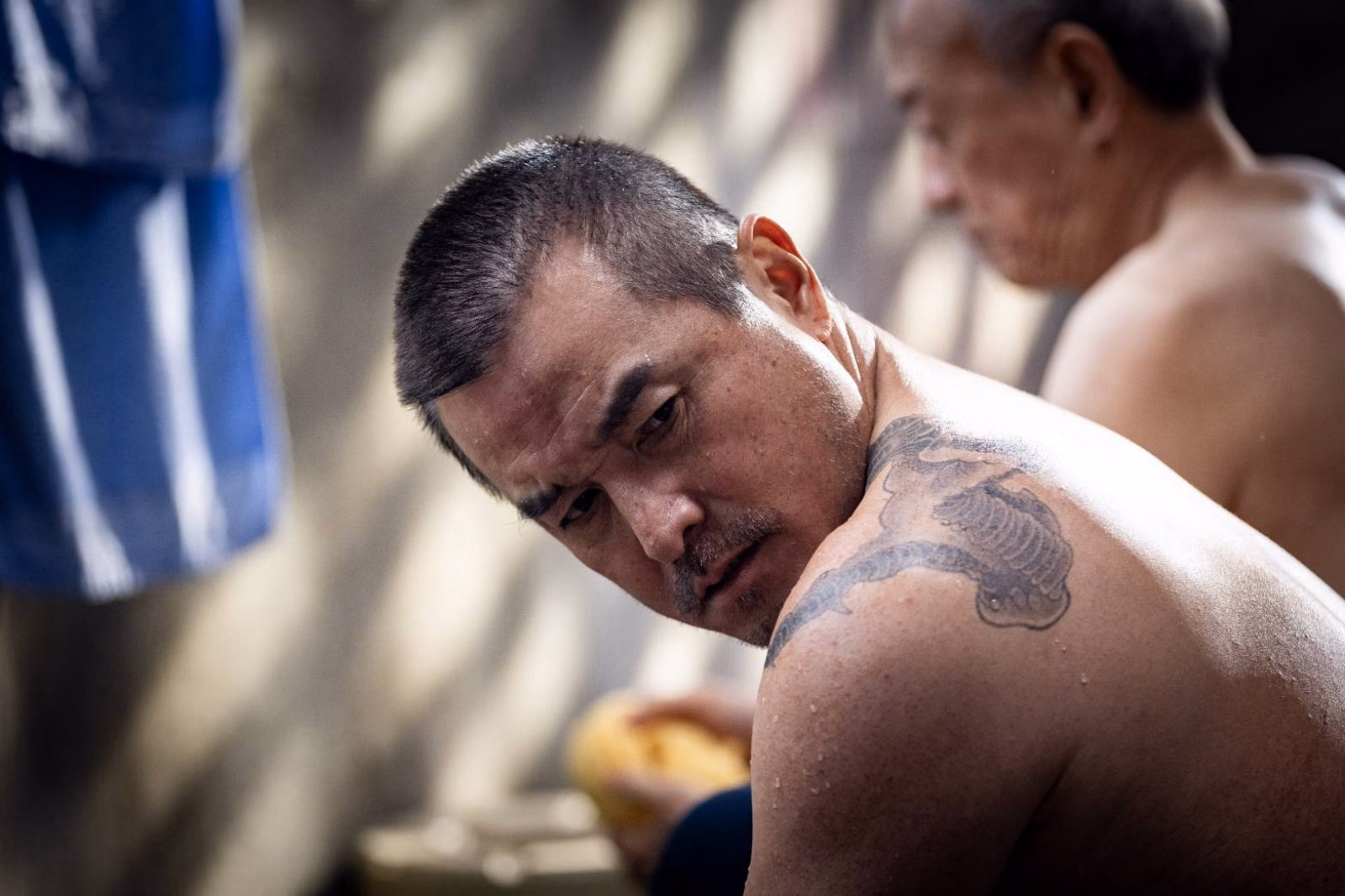 Fictional film still of 李銘順’s character looking back with a shoulder tattoo visible