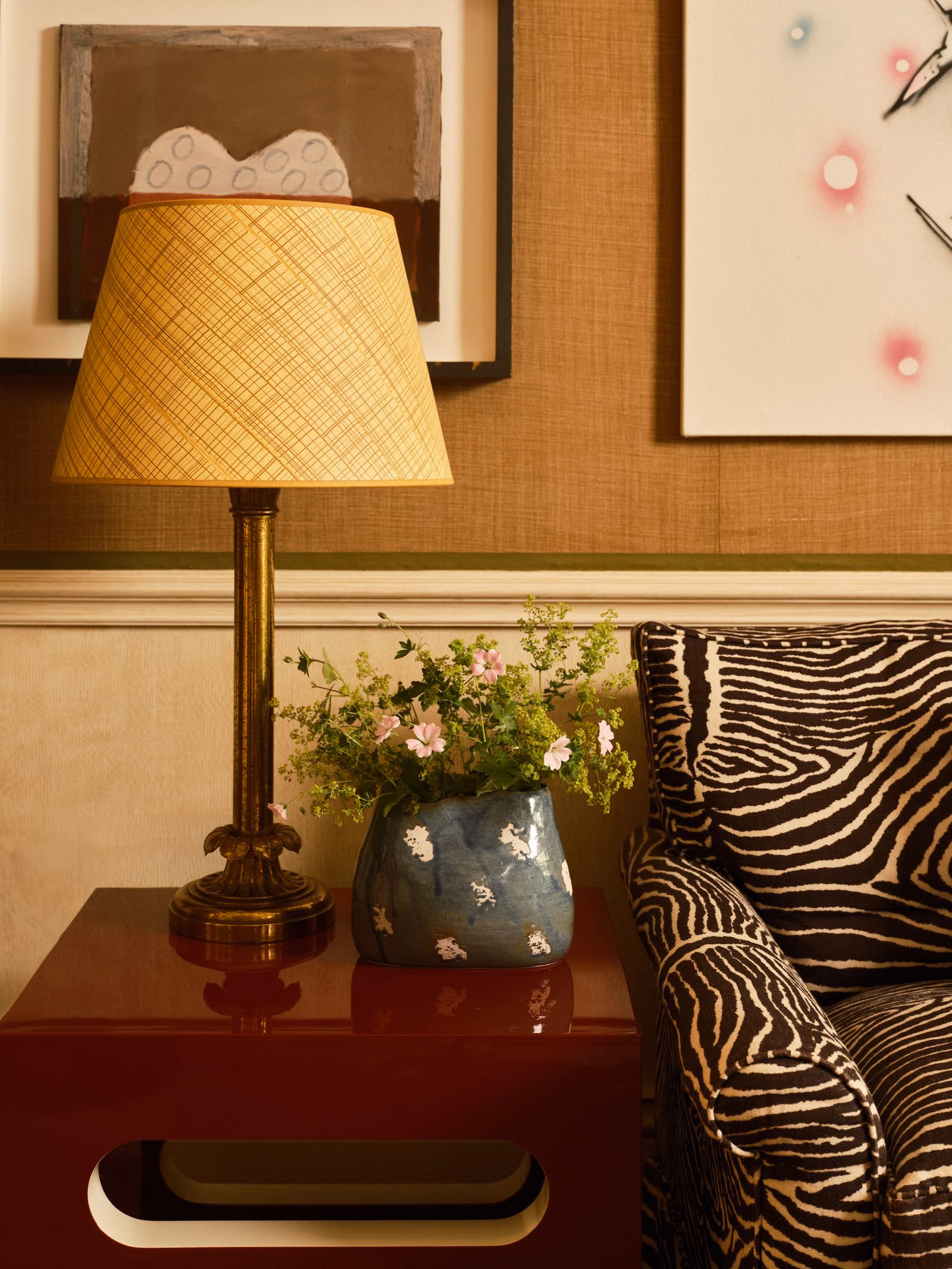 A blue-green bag-shaped vase beside a yellow lampshade and zebra-patterned seat